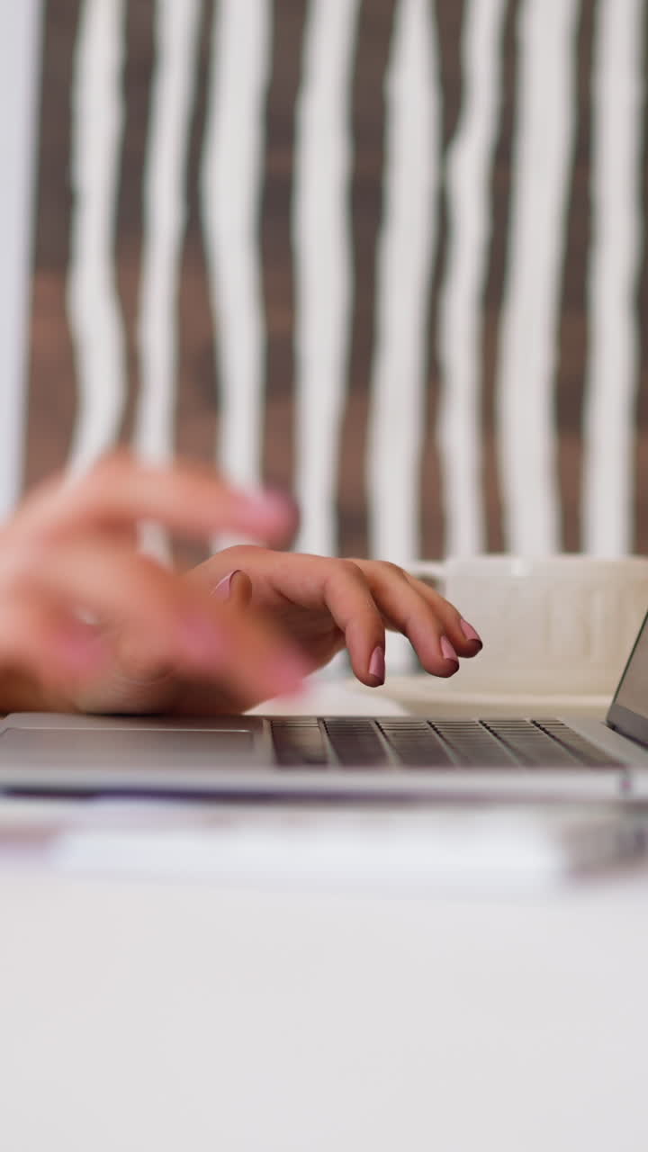 Woman in beige shirt makes calculations on numeric keypad comparing with data on laptop screen at white desk in office room closeup slow motion