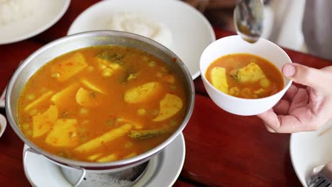 ladling yellow curry into a bowl