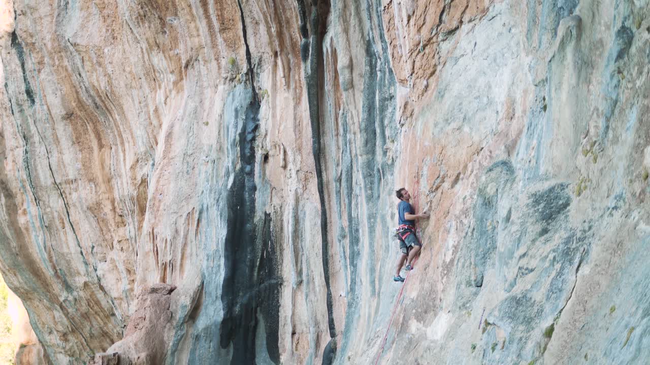 Sport climber ascending a vertical mountain wall