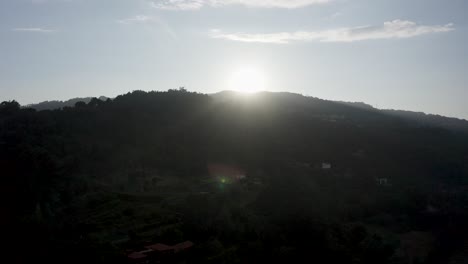 Aerial-of-the-sun-shining-brightly-over-the-mountains-with-blue-sky-in-background