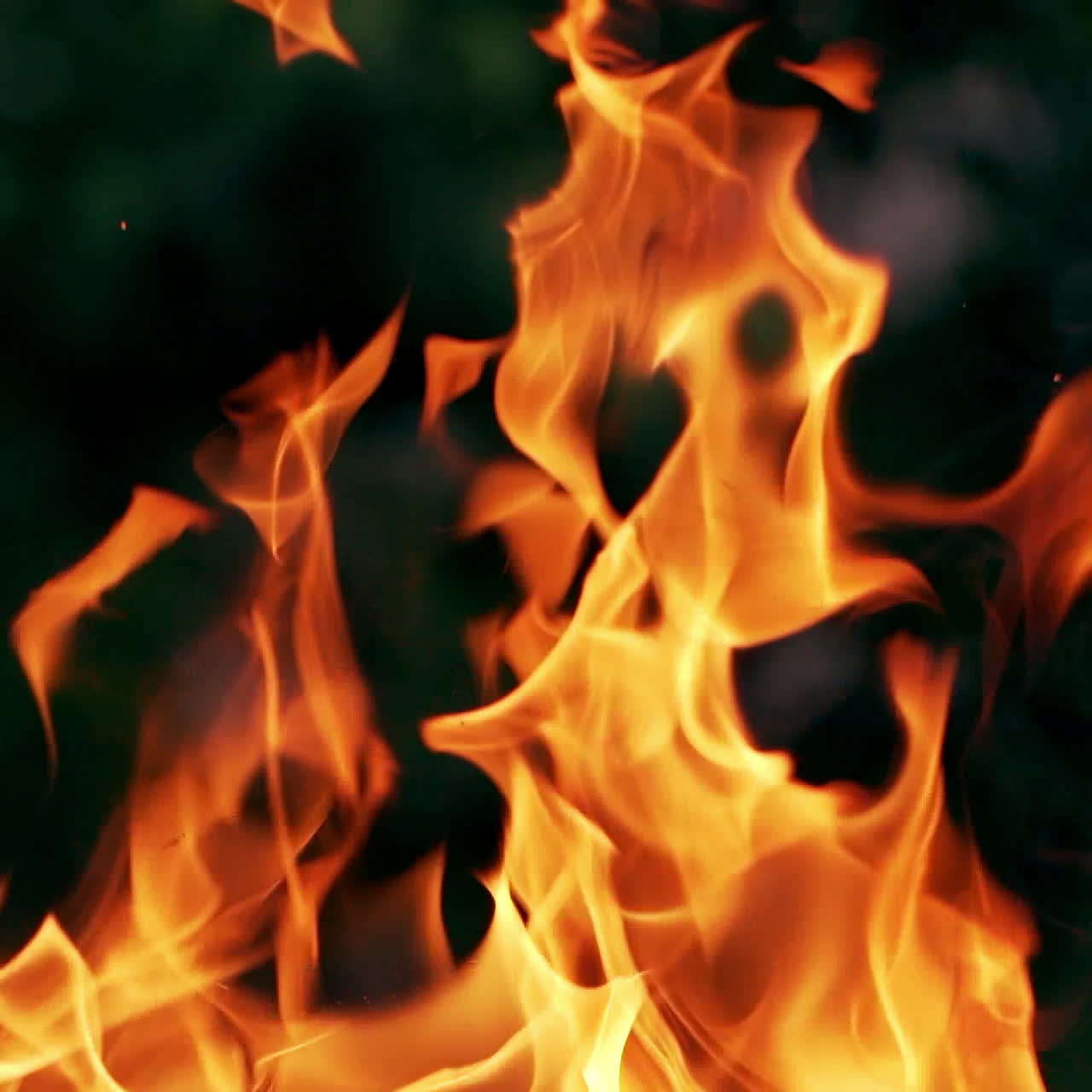 Twisting tongues of flame on dark background. Close-up of magnetic flame of outdoor shot. Slow motion.