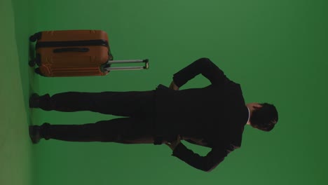 full body of back view asian businessman traveler with luggage standing with arms akimbo in the green screen background studio, during sunset time