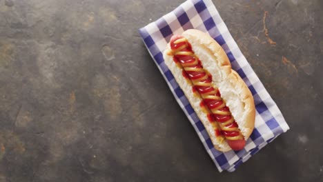 video of hot dog with mustard and ketchup on a black surface