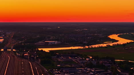 glowing sunset in red and orange tones above a calm river and scenic landscape