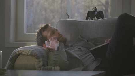 Caucasian-man-relaxed-on-couch-working-on-phone-with-agenda-in-hand