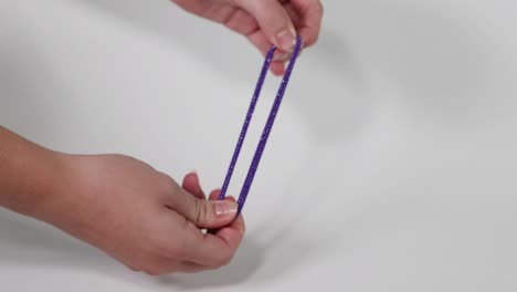 hands pulling a sparkly purple hair tie