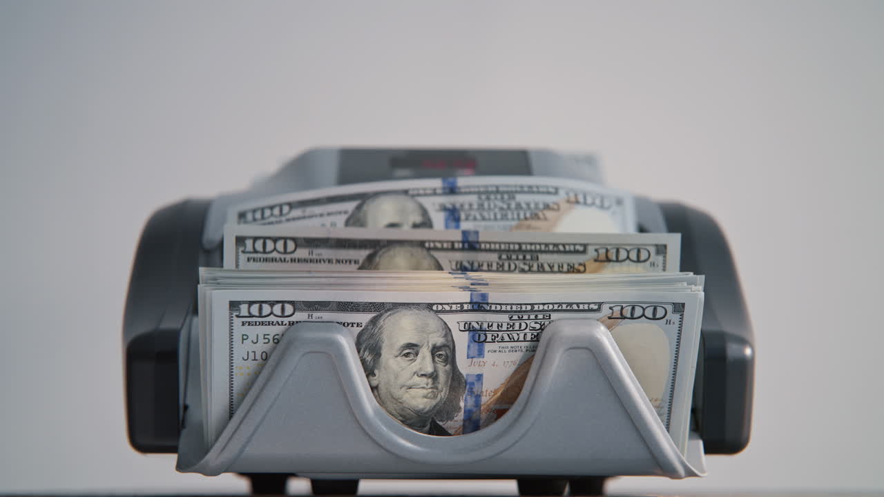 Electronic counter calculating hundred dollar banknotes closeup. Money counting