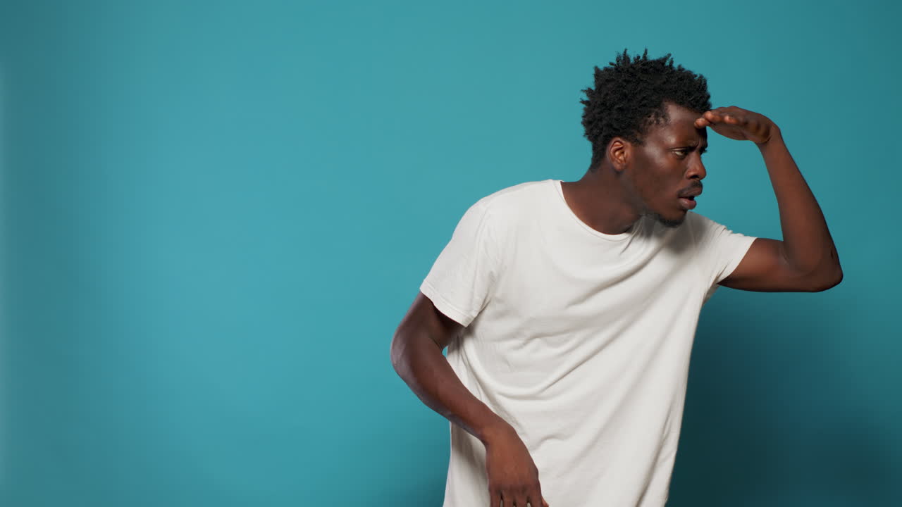 Casual person looking into distance with hand at forehead