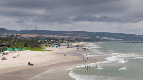 A-Scene-of-People-Enjoying-Beach-on-a-Cloudy-Forecast-Day-at-Malibu,-Mui-Ne,-Vietnam---Aerial-Panning