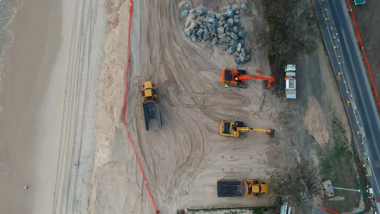 imágenes de drones de maquinaria de construcción grande utilizada para reparar dunas de arena de playa dañadas por el oleaje reciente de un ciclón tropical
