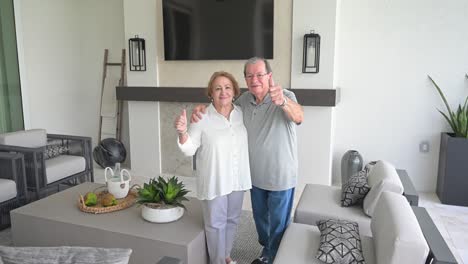 una pareja feliz da un pulgar hacia arriba a sus nuevos muebles modernos al aire libre afuera en su área de lanai en su casa recién construida