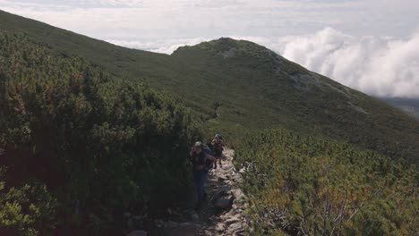 tourists walking on the hiking trail to the krivan summit in slovakia on a bright sunny day - wide shot
