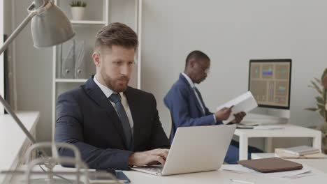 businessman working on laptop and making phone call in office