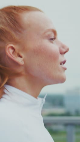 a close-up of a joyful athletic woman with flowing red hair, captured in motion as she enjoys an invigorating outdoor workout, highlighting her determination and vitality
