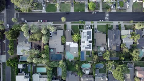 Birdseye-aerial-view-above-Van-Nuys-residential-homes-rooftops-streets-pools-and-property-gardens