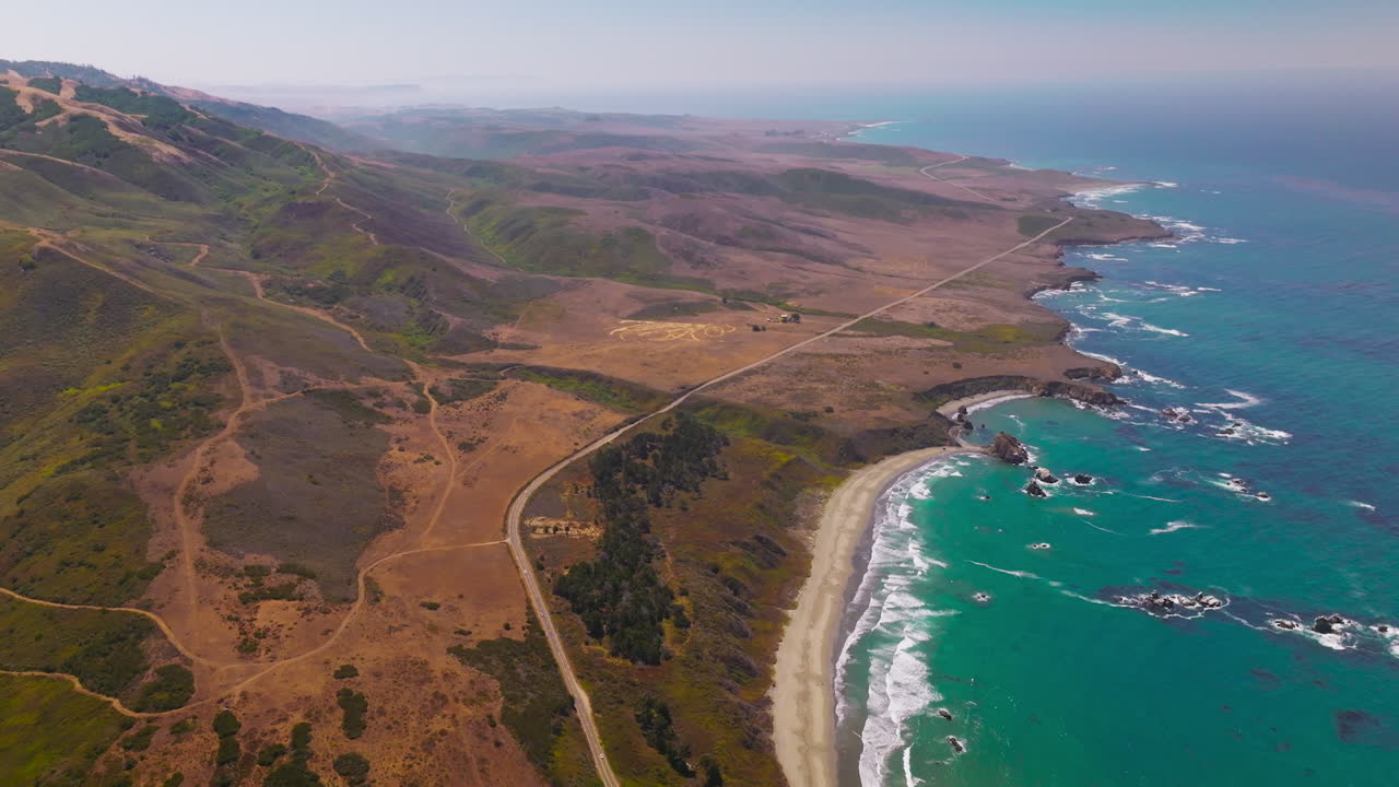 Flight over the mountainous shore of the Pacific ocean in California, USA. Highway going along the rocky landscape along the water.