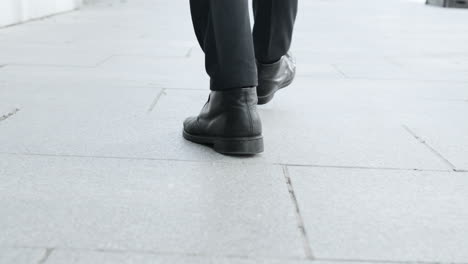 businessman feet walking on urban street. employee in black shoes going for work