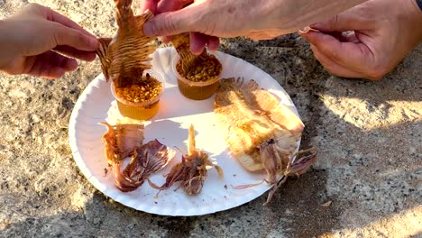 hands sharing grilled seafood on a plate