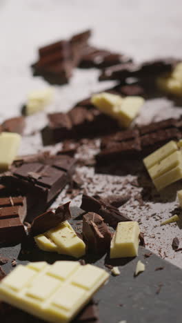 vertical video of grated chocolate being dropped on broken bars of milk plain and white chocolate