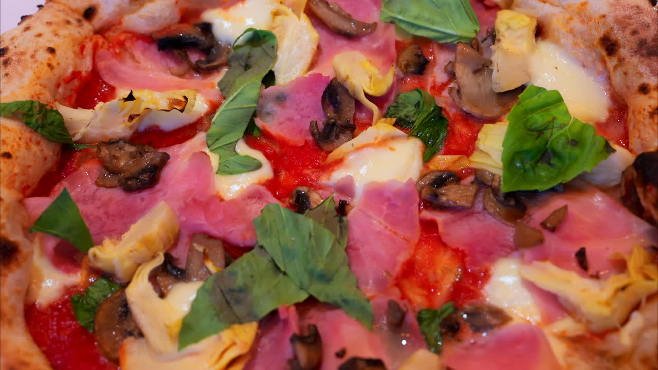 Close up of pizza with artichoke, ham, mushrooms and basil