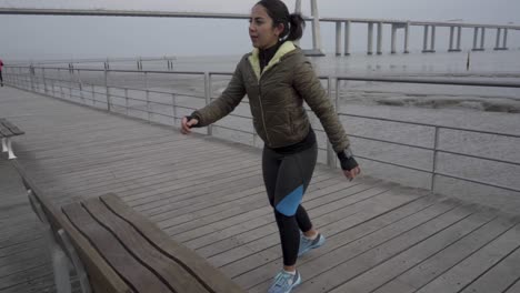 joven hindú confiada entrenando en la orilla del mar