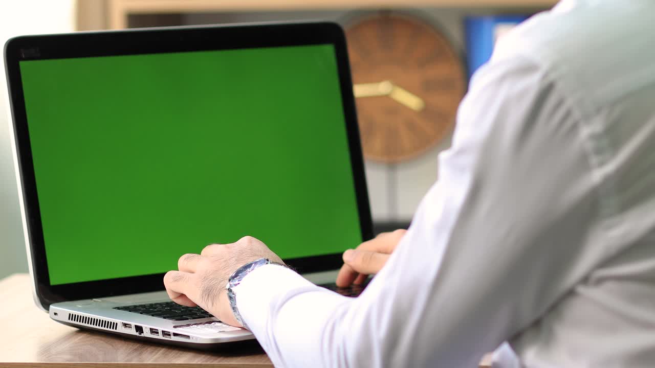 hombre trabajando en una computadora portátil con pantalla verde