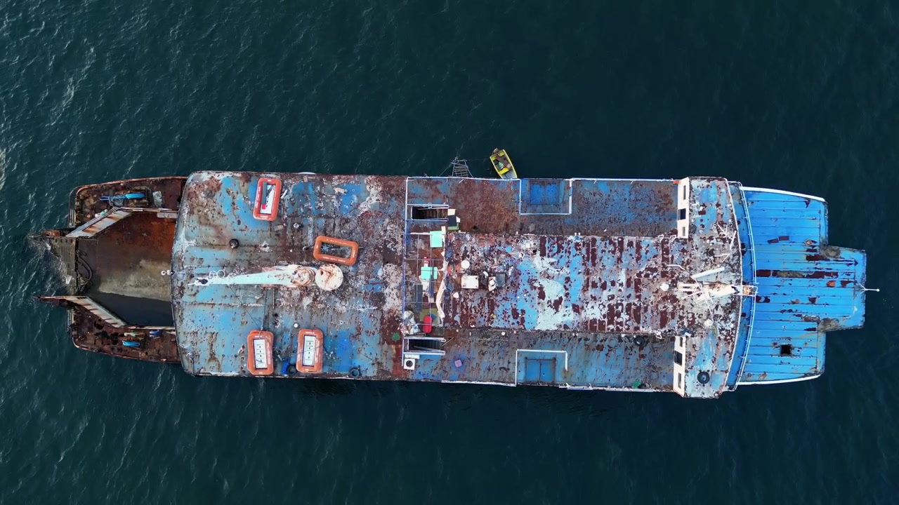 Close-up aerial footage around a decaying rusty cargo vessel surrounded by vast ocean near Batangas Port Batangas Philippines.