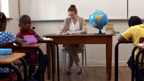 Profesor-Sentado-En-La-Parte-Superior-Del-Aula