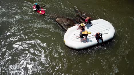 Vista-De-Drones-De-Cerca-De-Un-Bote-De-Rafting-Al-Revés-Y-Kayaks-De-Seguridad-En-El-Río-Nilo,-Jinja,-Uganda