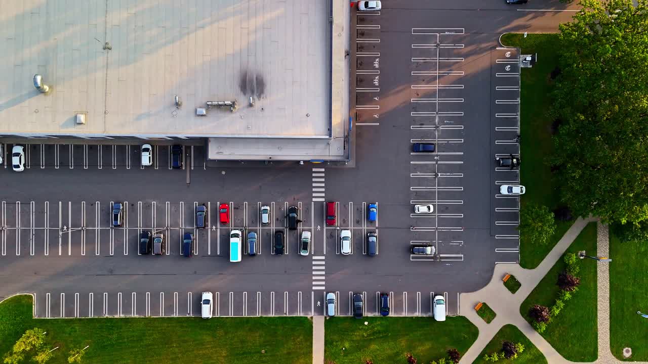 Top down view of parking lot with parked cars, road markings, crosswalk and shadows