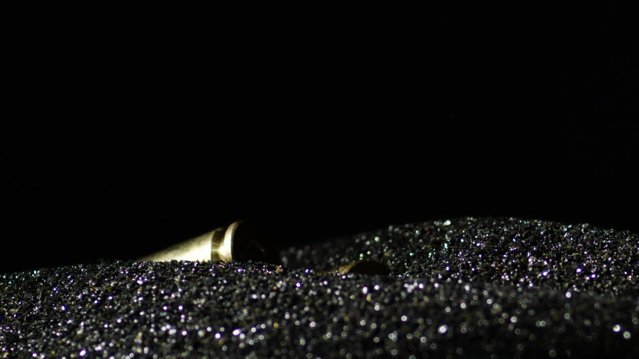Cartucce avanzate per fucile da 6mm che cadono su un mucchio di polvere da sparo su sfondo nero