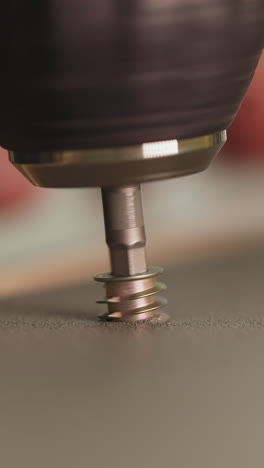 employee screws short fixture with electric screwdriver in workshop closeup. carpenter assembles furniture with manual instrument. connecting parts