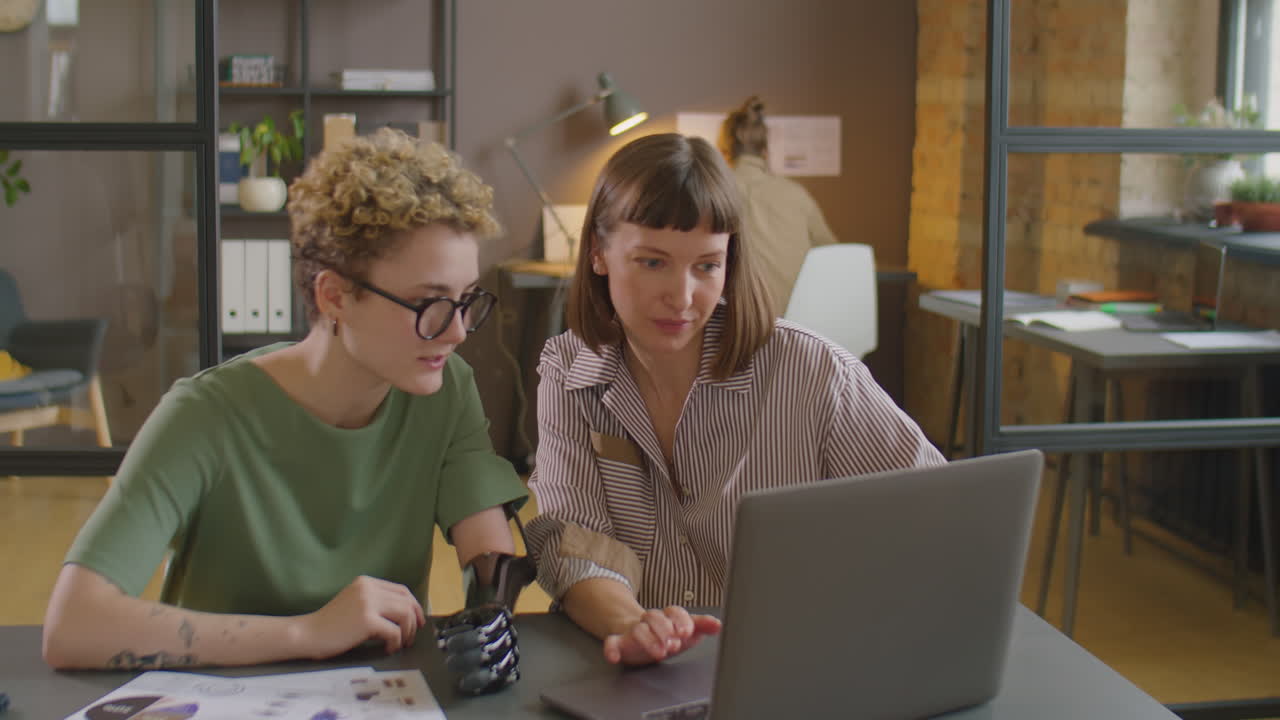 Businesswoman with Prosthetic Arm Working with Colleague in Office