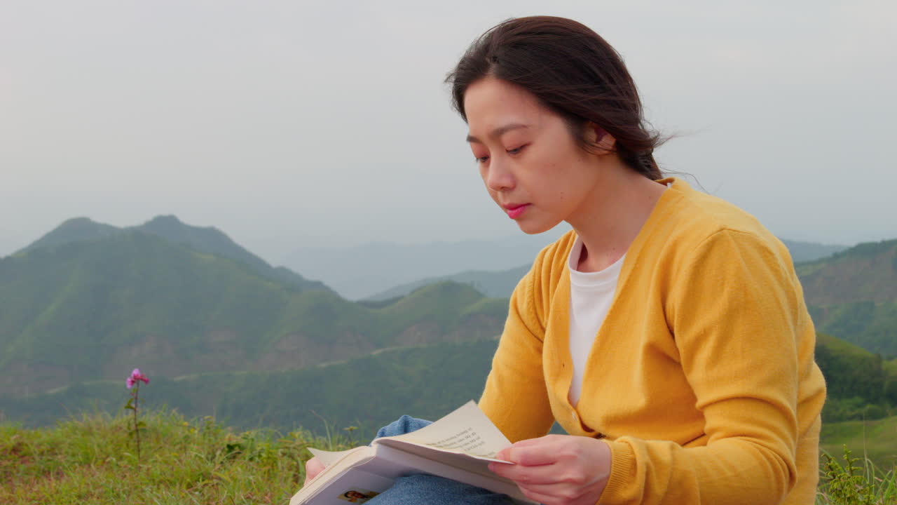 산 위 에 앉아 평화로운 시골 에서 읽고 있는 젊은 여자