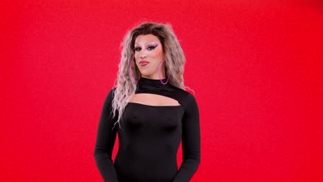 drag queen in black dress posing on red backdrop