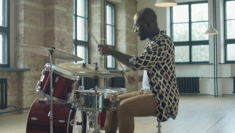black drummer playing music in loft studio