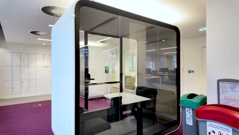 futuristic glass walled office pod provides a quiet workspace for focused work and important calls in a shared office environment