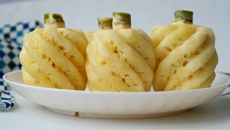 close-up of three sliced pineapples on a white plate