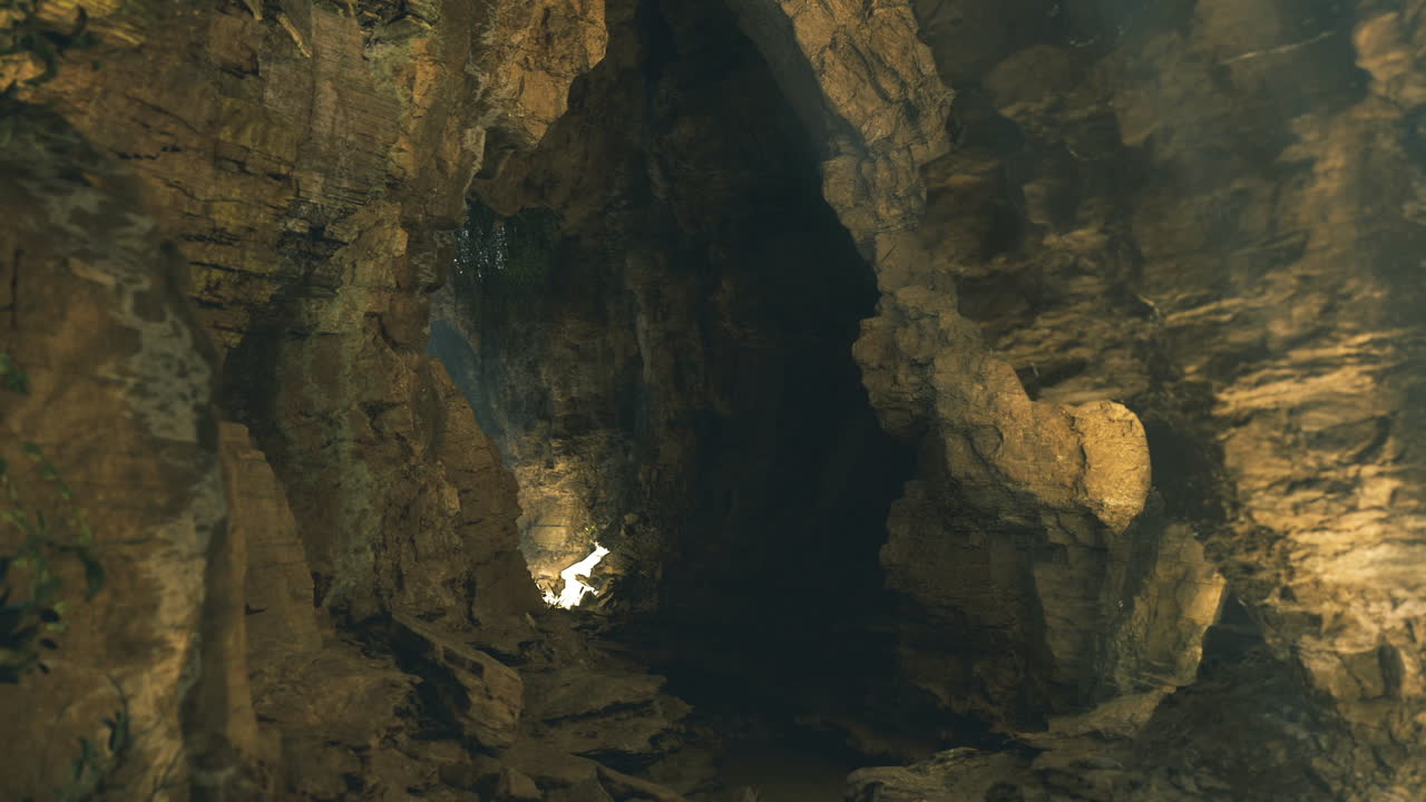 Grotta calcarea scura con pareti texturizzate e luce misteriosa.