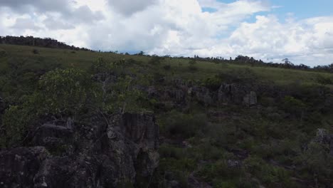 aerial skims jagged surreal rocky slope up and over natural stone arch