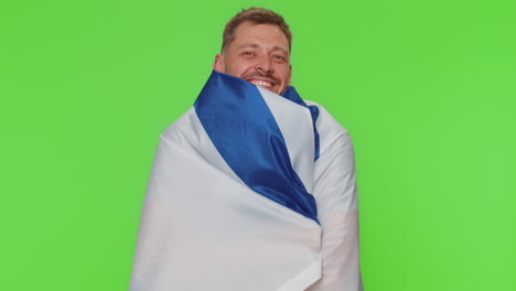 joven con camiseta gris agitando y envolviendo la bandera nacional de israel, celebrando el día de la independencia