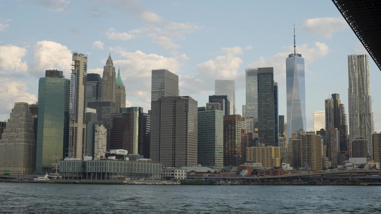 Vista cinematográfica en cámara lenta que revela el horizonte de la ciudad de Nueva York, con el Puente de Brooklyn, el East River y los icónicos rascacielos de Manhattan