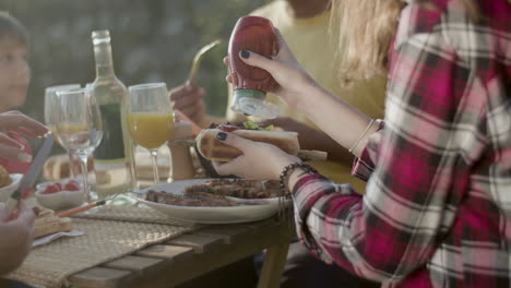 primer plano de una adolescente exprimir ketchup en su perrito caliente