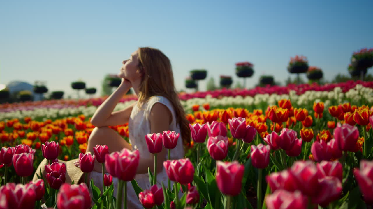 mujer joven sonriendo en el jardín de flores brillantes. perfil de mujer en el fondo de la flor.