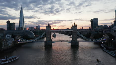 Forwards-fly-above-Thames-River-towards-old-and-famous-Tower-Bridge.-Low-flight-above-top-walkway.-Colourful-sunset-sky.-London,-UK