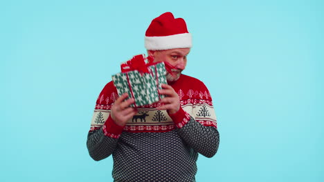 Funny-man-wears-Christmas-sweater-with-deers-received-present,-interested-in-what-inside-gift-box