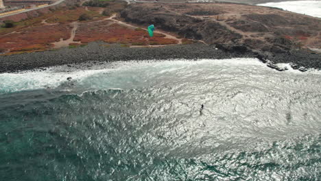 Aerial-view-of-a-person-kitesurfing-near-the-shore-on-a-windy-day