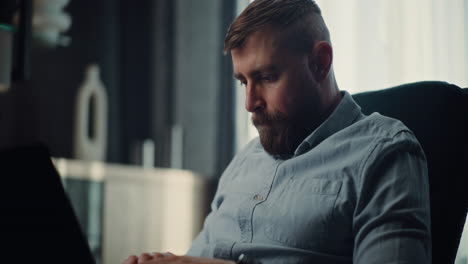 concentrated professional stock exchange broker using laptop, monitoring real-time stocks and exchange market charts. successful investment agent working on trading in cozy office of financial agency.