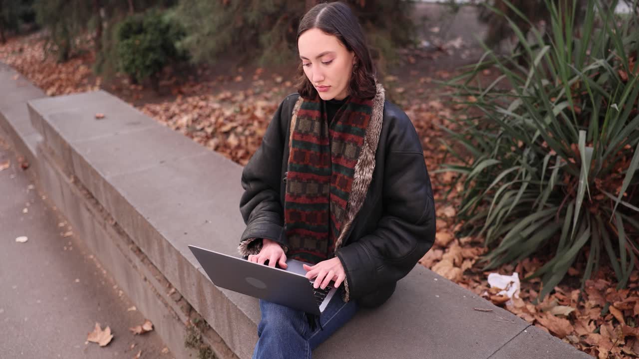 Woman working on laptop in autumn park
