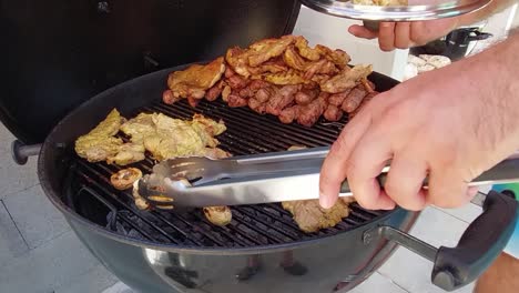 hombre con abrazaderas de acero sacando champiñones asados de la parrilla de carbón